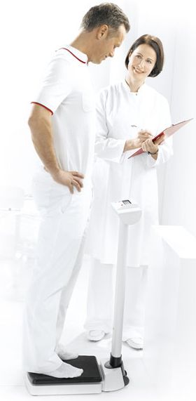 doctor standing beside patient weighing
